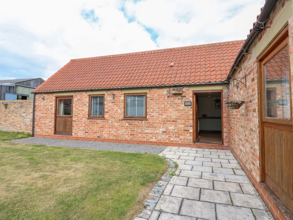 An outdoor view of a cottage with brick walls and a door at Cooper Cottage Potto near Stokesley