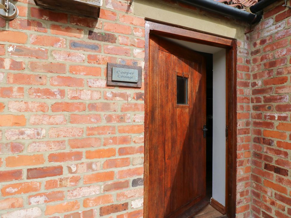 An entrance with a wooden door and brick wall at Cooper Cottage near Stokesley