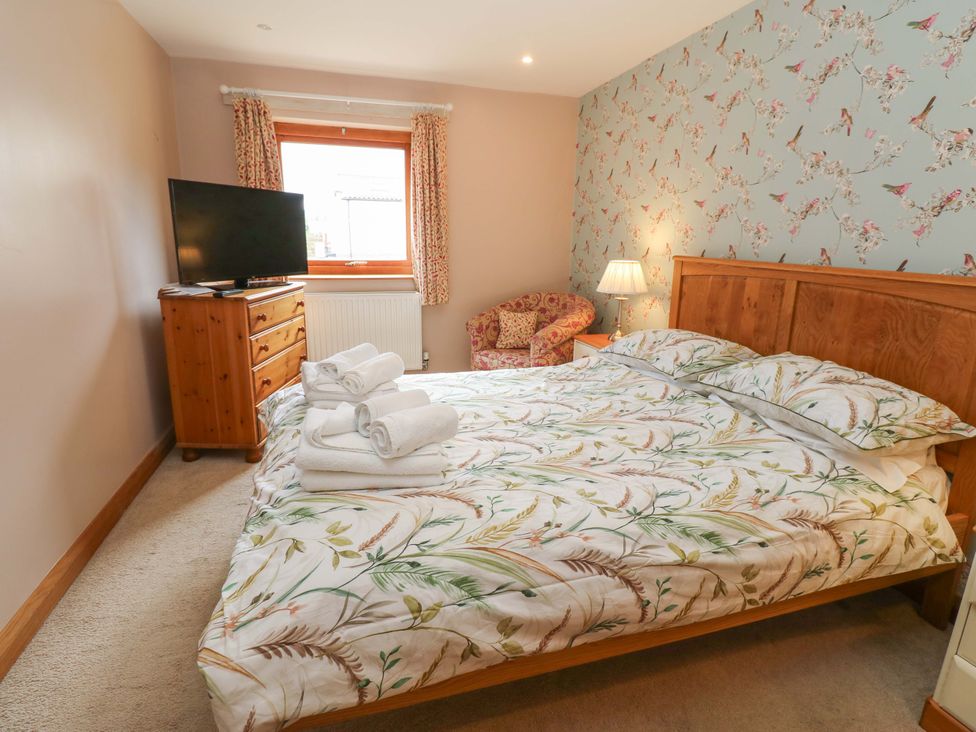 A bedroom with a bed and television at Cooper Cottage in Potto near Stokesley