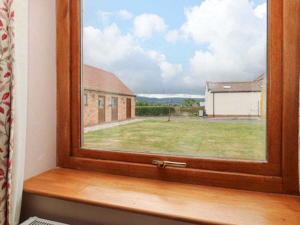 A view from a window showing grass and buildings at Cooper Cottage Potto near Stokesley