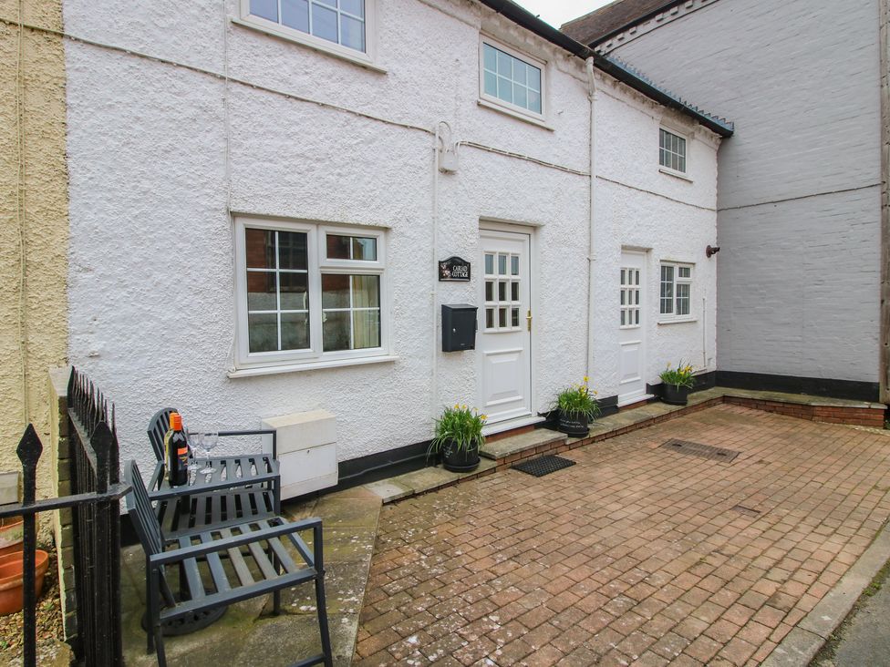 An outdoor view of a house with a bench and a mailbox at Cariad Cottage in Ludlow