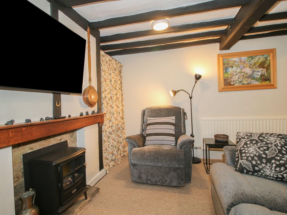 A living room with a fireplace and armchair at Cariad Cottage in Ludlow