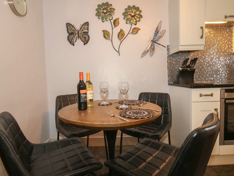 A dining area with a round table and wine bottles at Cariad Cottage in Ludlow