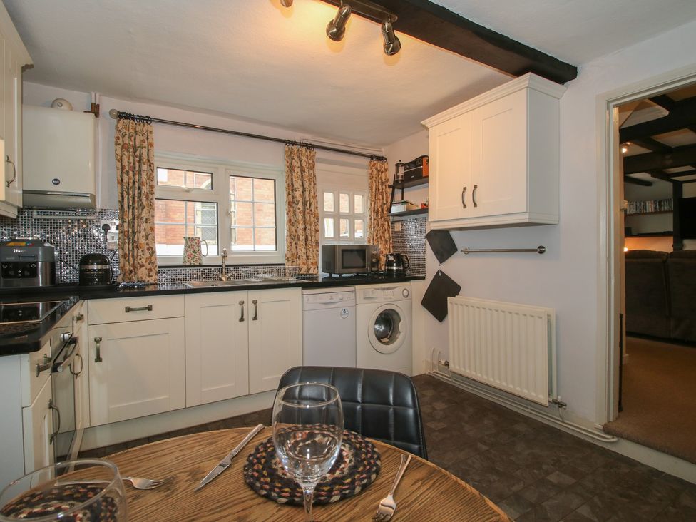 A kitchen with appliances and a dining table at Cariad Cottage in Ludlow