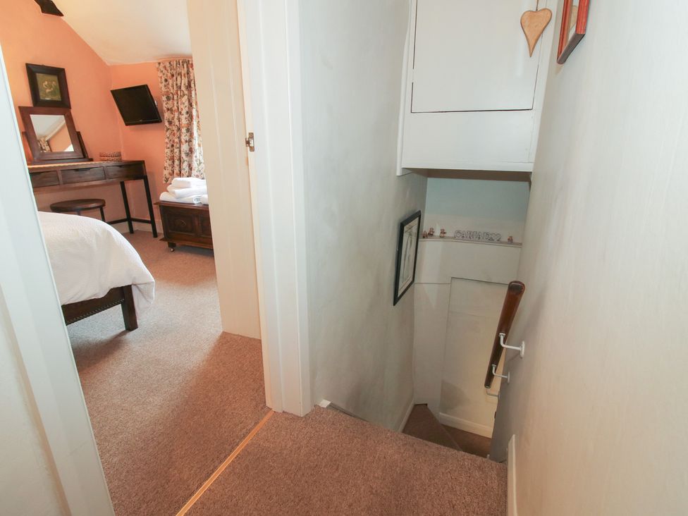 A staircase leading to a bedroom featuring a bed and decorative items at Cariad Cottage in Ludlow