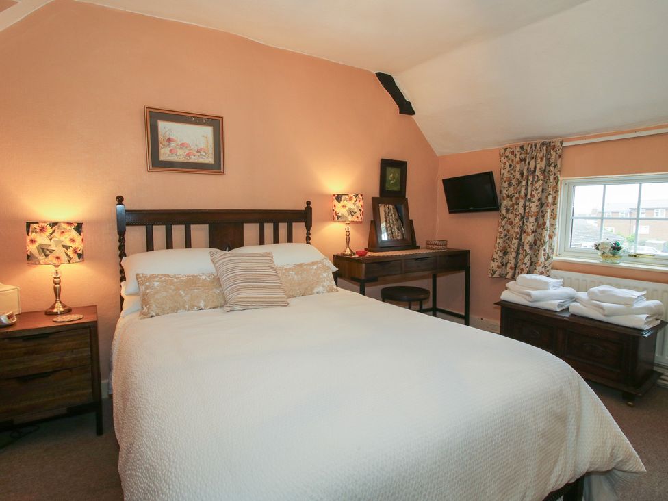 A bedroom with a bed and nightstand at Cariad Cottage in Ludlow