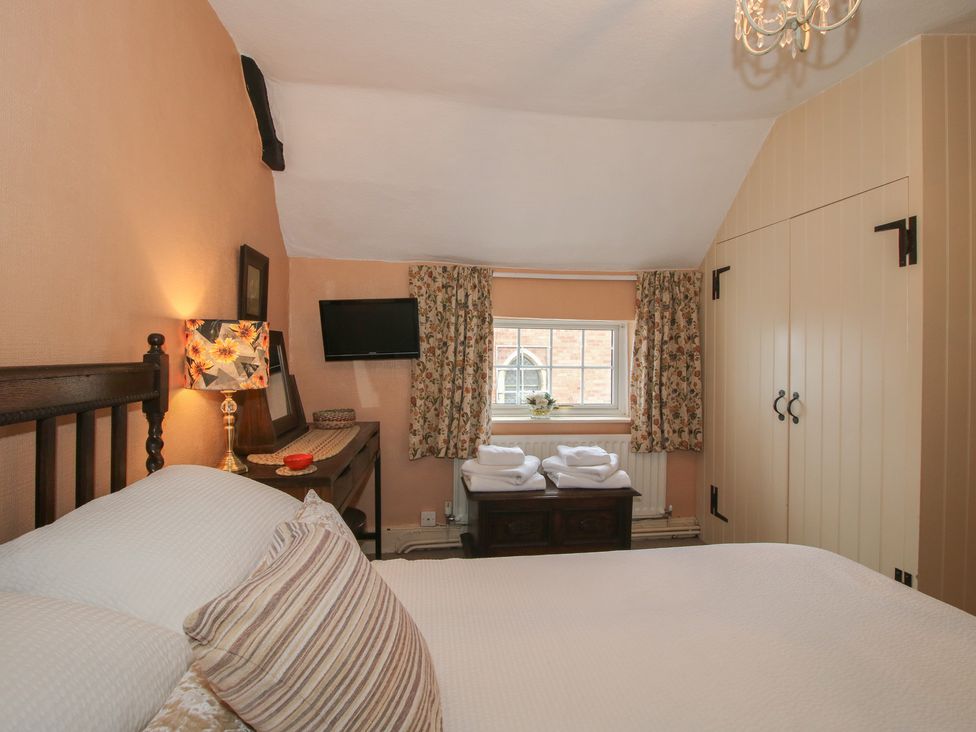 A bedroom with a bed and dresser at Cariad Cottage in Ludlow
