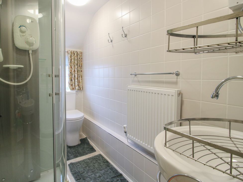 A bathroom with a shower, toilet, sink and towel rack at Cariad Cottage Ludlow