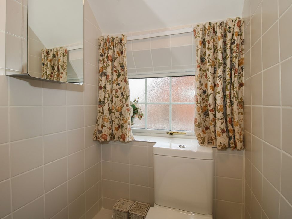 A bathroom with a toilet and mirror at Cariad Cottage in Ludlow