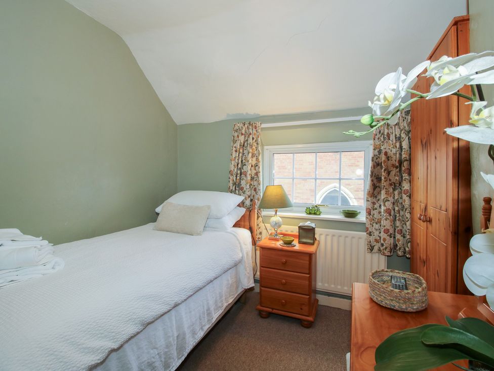 A bedroom with a single bed and wooden furniture at Cariad Cottage in Ludlow