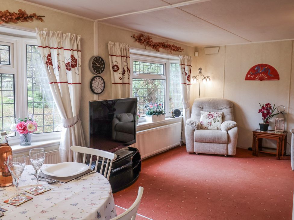 A living room with a sofa, dining table, and television at The Lodge in Old Buckenham near Attleborough