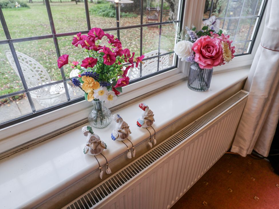 A living room with flowers and figurines on a windowsill at The Lodge Old Buckenham near Attleborough