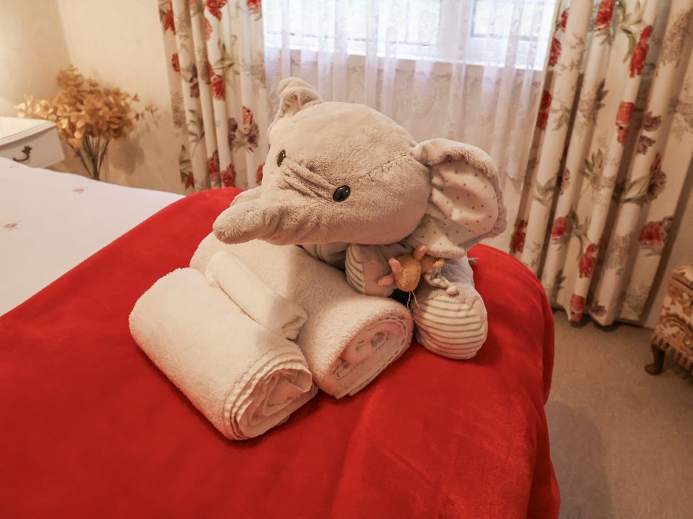 A teddy bear and rolled towels on a bed in The Lodge near Old Buckenham
