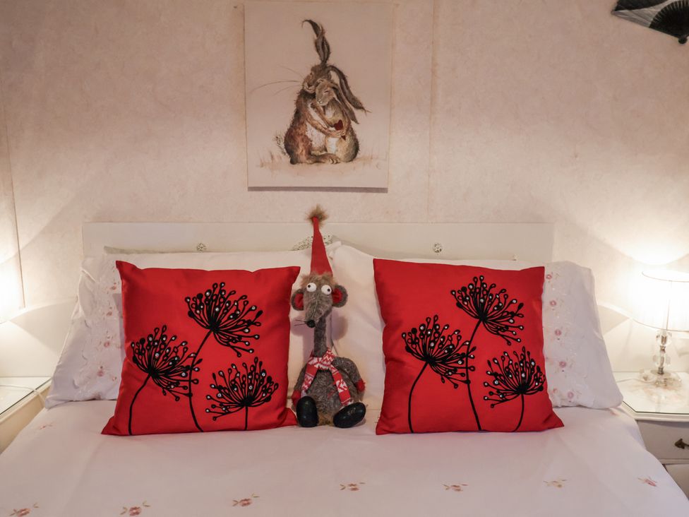 A bed with red pillows and a stuffed animal in a bedroom at The Lodge in Old Buckenham near Attleborough