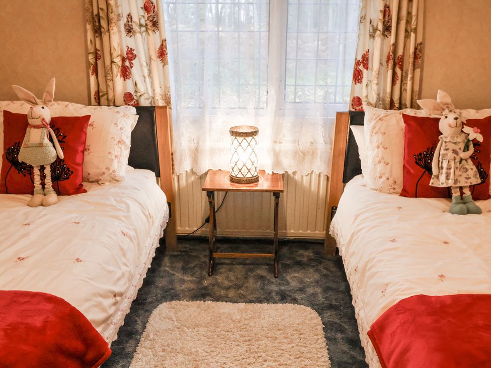 A bedroom with two beds and a lamp on a side table at The Lodge in Old Buckenham near Attleborough
