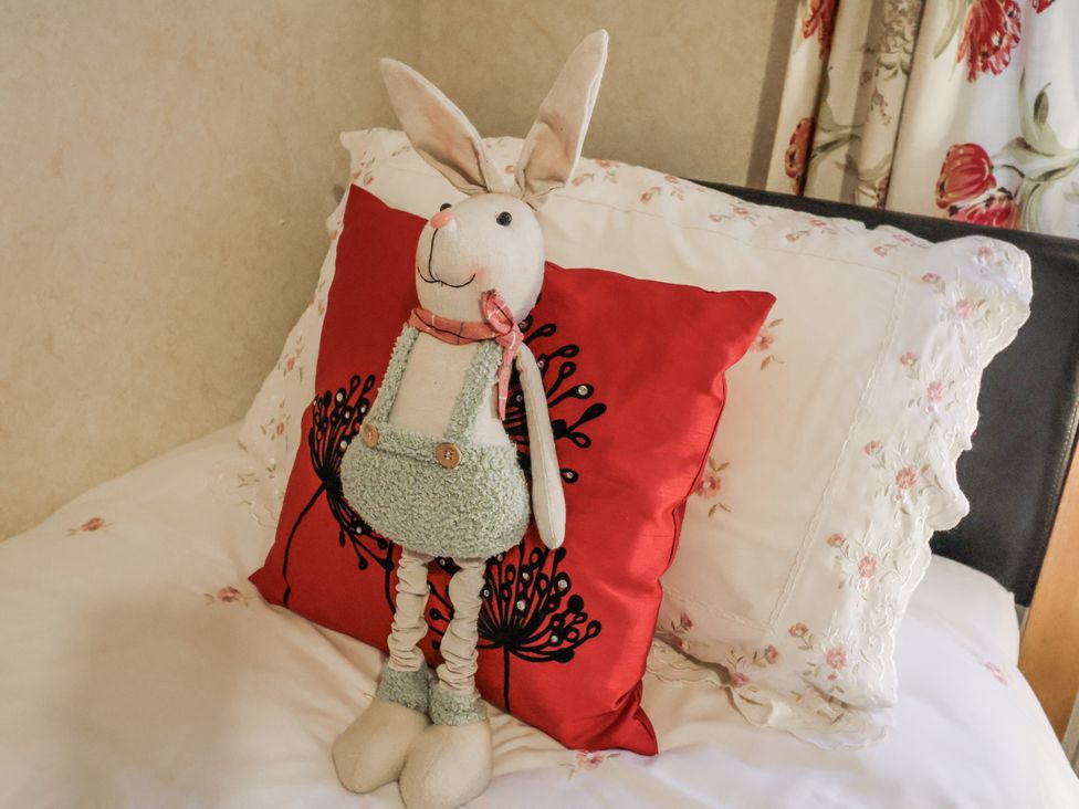 A stuffed rabbit on a red pillow in a bedroom at The Lodge in Old Buckenham near Attleborough