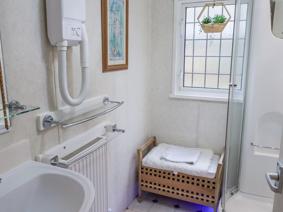 A bathroom with a shower, towel rack, and radiator at The Lodge in Old Buckenham near Attleborough