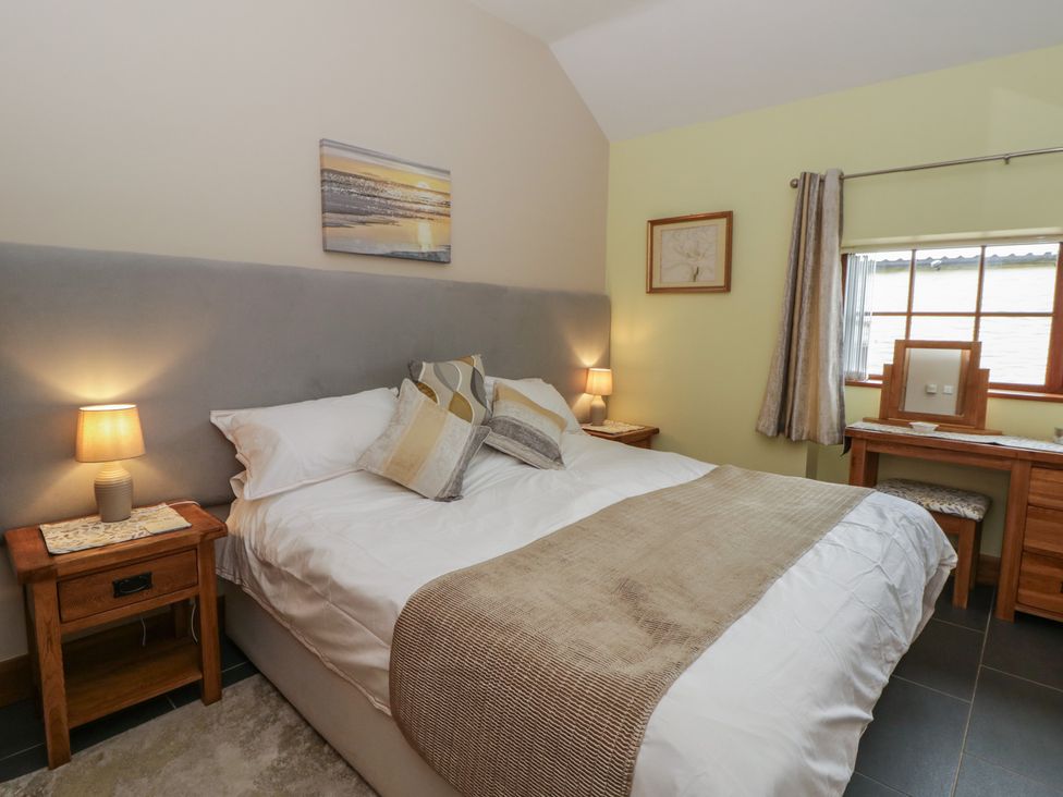 A bedroom with a bed and a dressing table at Yr Hen Llaethdy in Blaen-Cil-Llech near Newcastle Emlyn