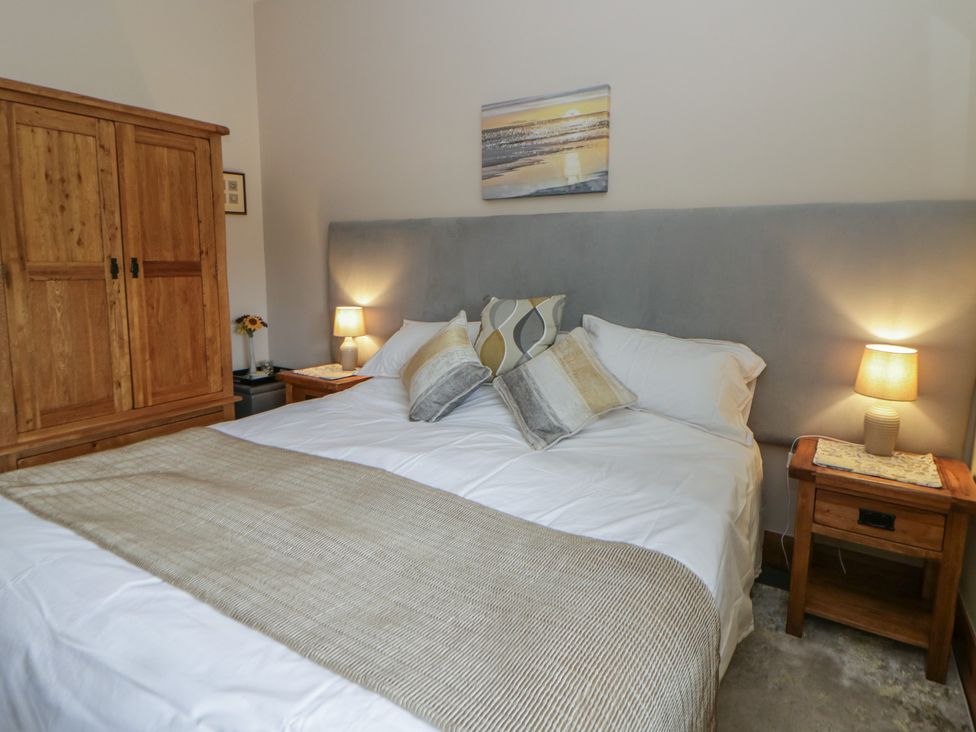 A bedroom with a bed and wooden wardrobe at Yr Hen Llaethdy near Blaen-Cil-Llech