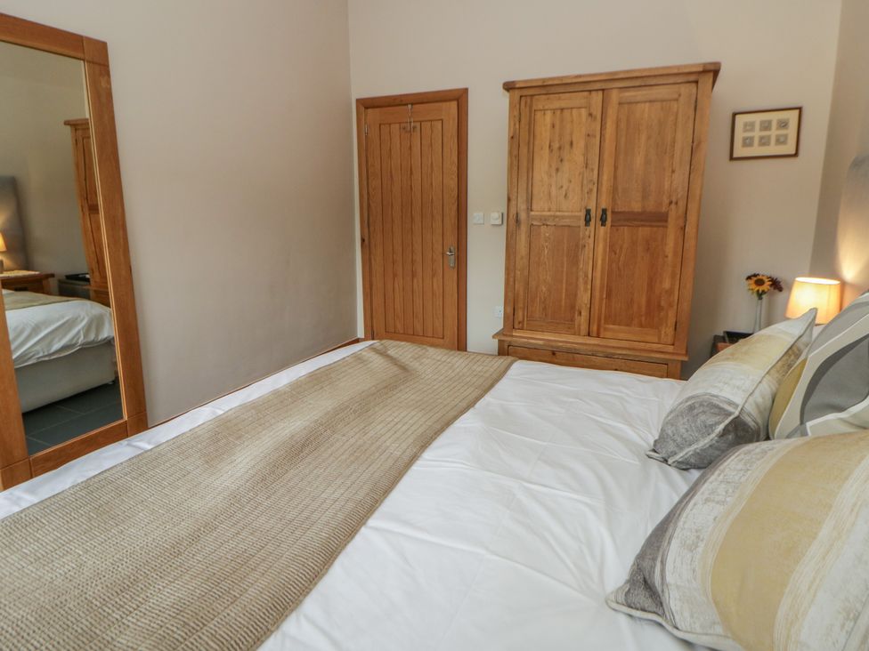 A bedroom featuring a bed with pillows and a wardrobe at Yr Hen Llaethdy near Newcastle Emlyn