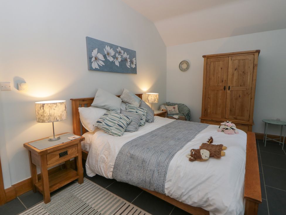 A bedroom with a bed, lamp, and wardrobe at Yr Hen Llaethdy in Blaen-Cil-Llech near Newcastle Emlyn
