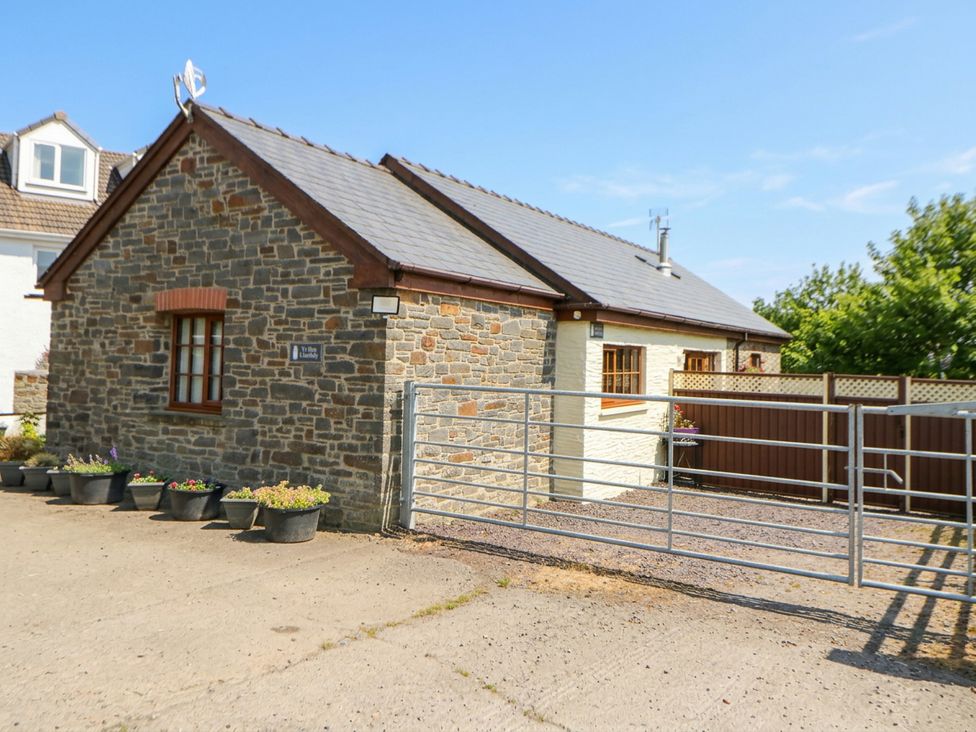 A stone house with a gate and potted plants at Yr Hen Llaethdy near Blaen-Cil-Llech