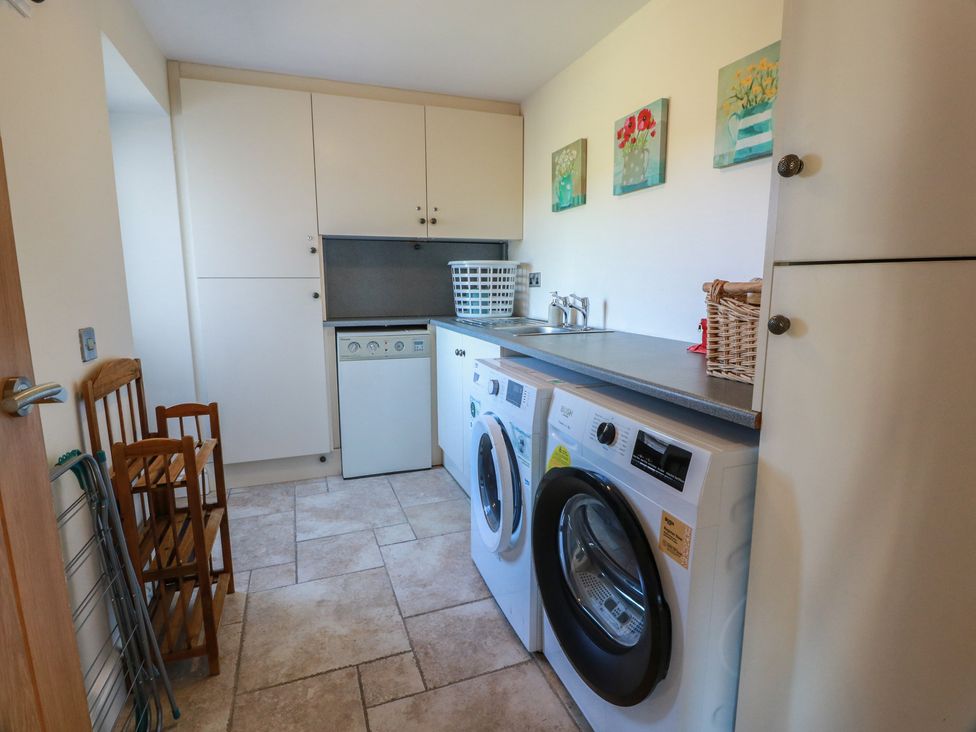 A utility room with washing machines and storage cabinets at South Milton Cottage Stairhaven near Glenluce