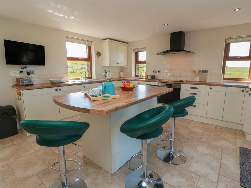 A kitchen with bar stools and kitchen appliances at South Milton Cottage Stairhaven near Glenluce