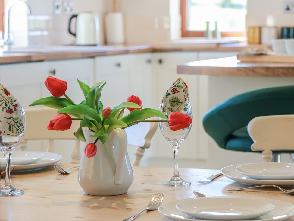 A dining table set with plates and a flower vase at South Milton Cottage Stairhaven near Glenluce