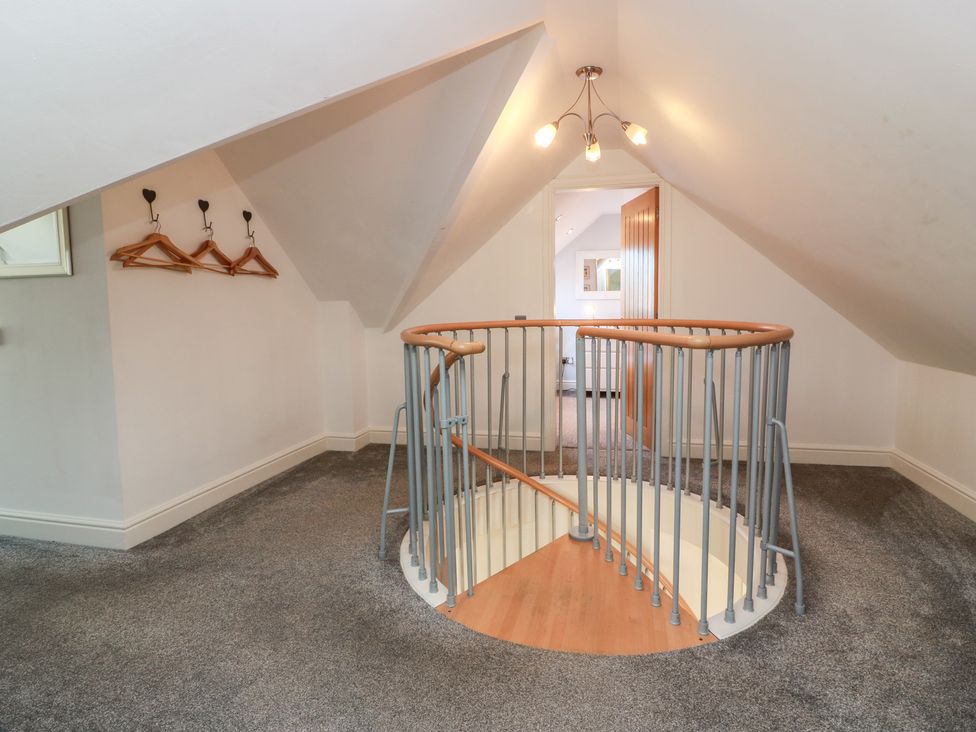 A landing with a spiral staircase and coat hooks at South Milton Cottage Stairhaven near Glenluce