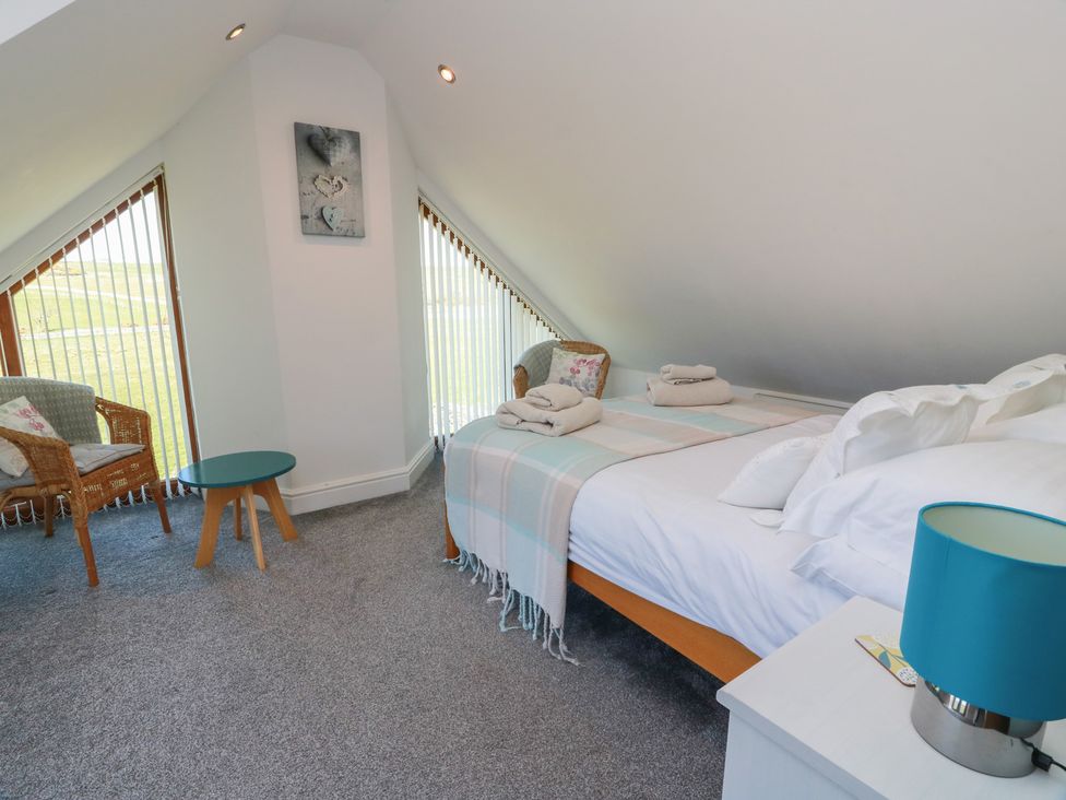 A bedroom with a bed and seating area at South Milton Cottage Stairhaven near Glenluce
