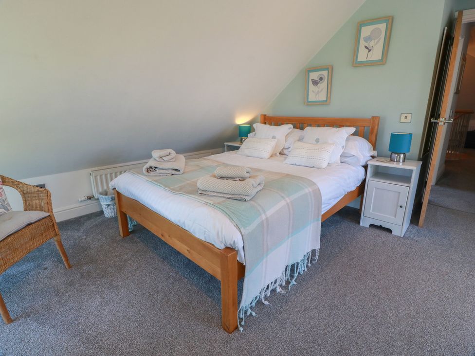 A bedroom with a bed and chair at South Milton Cottage Stairhaven near Glenluce