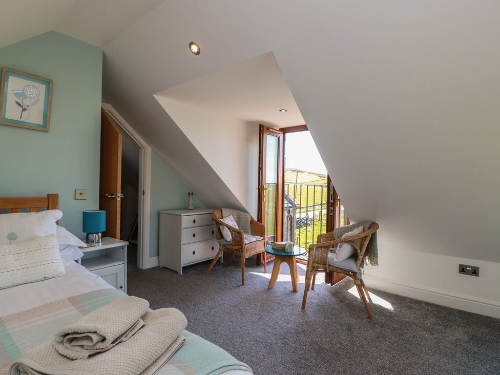 A bedroom with a bed and chairs at South Milton Cottage Stairhaven near Glenluce