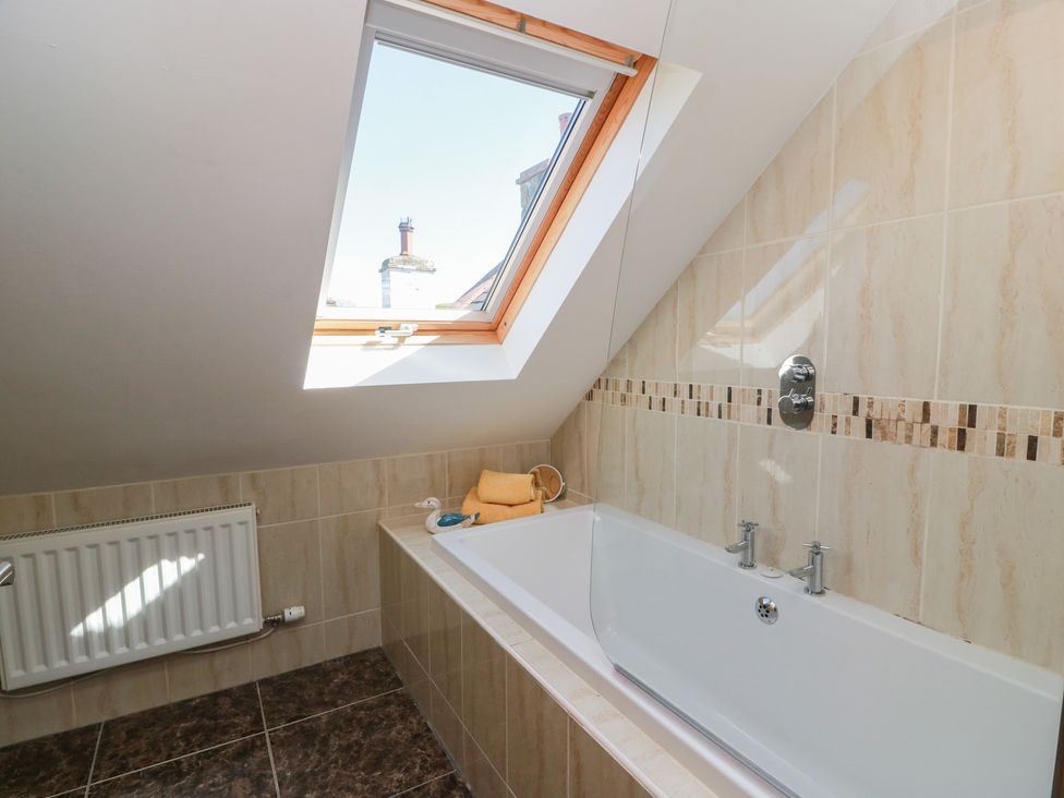 A bathroom with a bathtub and window at South Milton Cottage in Stairhaven near Glenluce