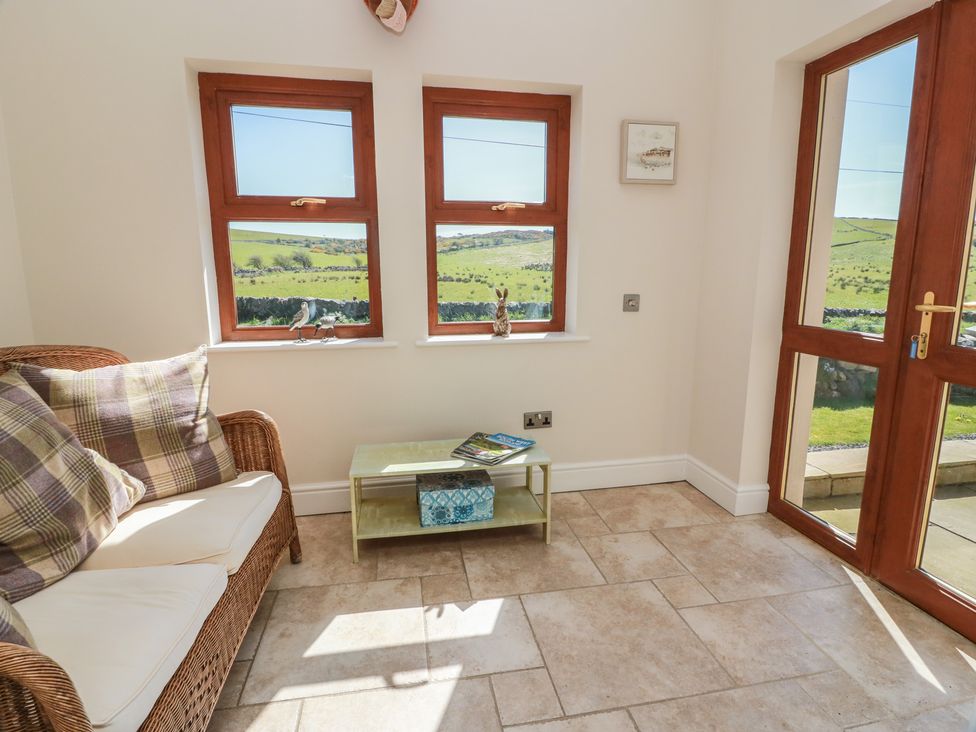 A snug with a sofa and windows at South Milton Cottage in Stairhaven near Glenluce