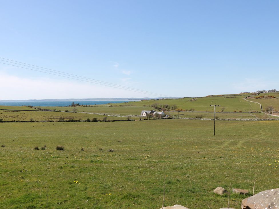 A field with a house and electricity pole at South Milton Cottage Stairhaven near Glenluce