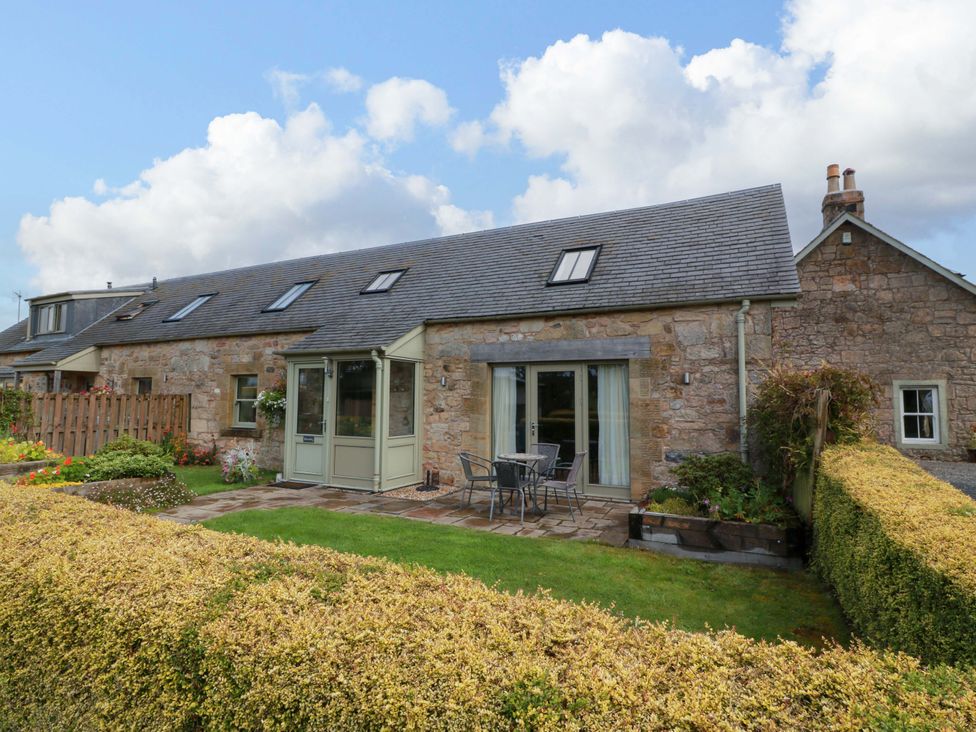 An outdoor view of a house with a garden and seating at Muirmailing Cottage Plean near Stirling