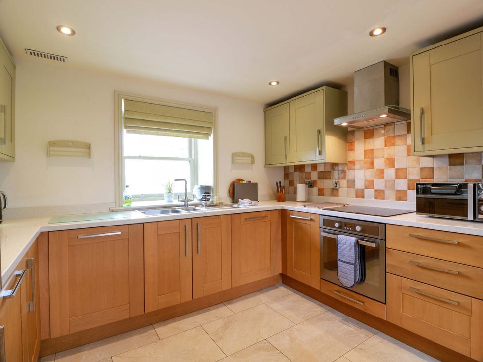 A kitchen with cabinets, sink, stove, and microwave at Muirmailing Cottage Plean near Stirling