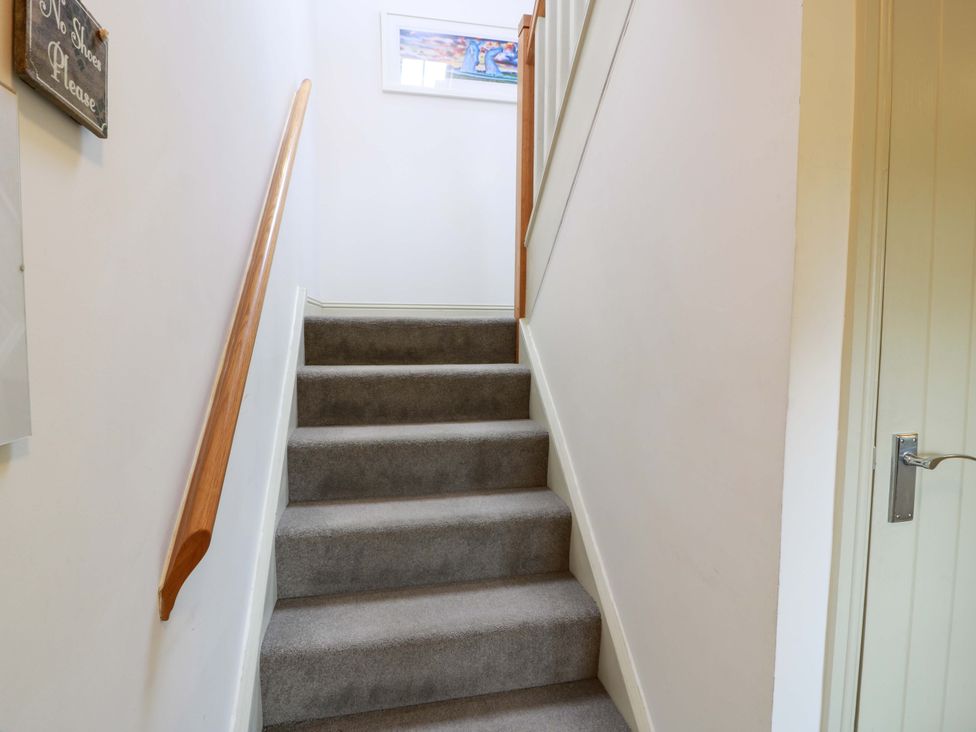 A staircase with carpeted steps and wooden handrail at Muirmailing Cottage, Plean near Stirling