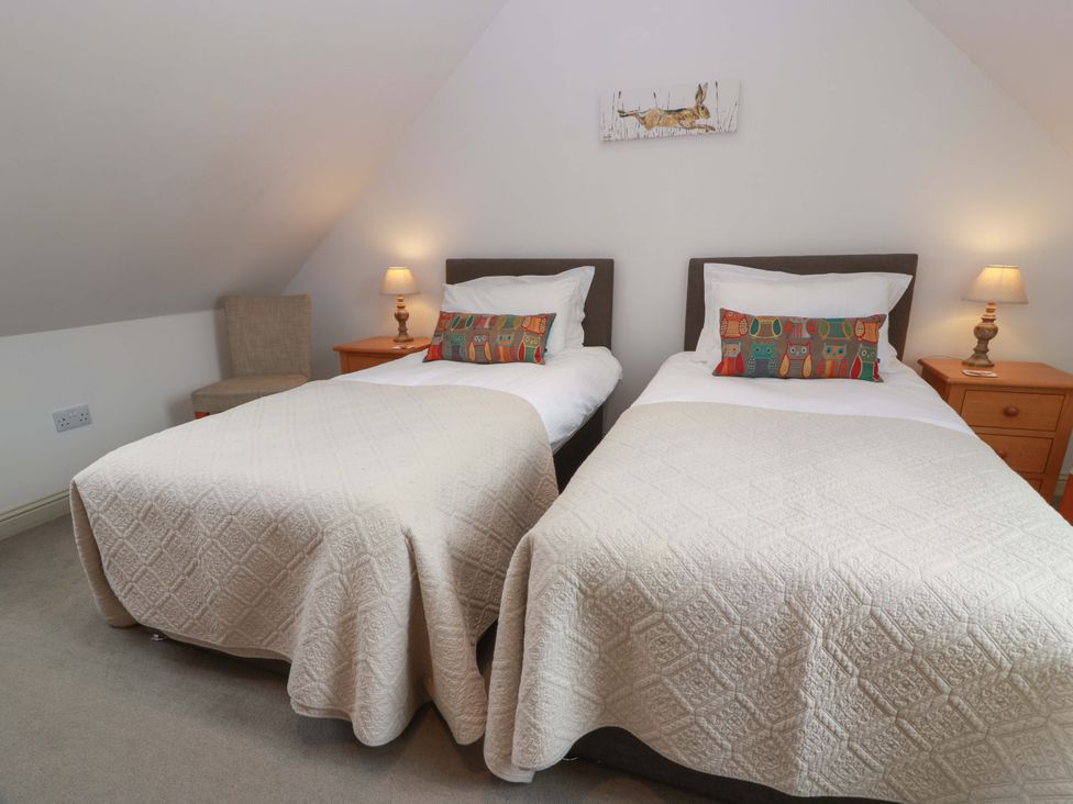 A bedroom with two beds and a lamp at Muirmailing Cottage in Plean near Stirling