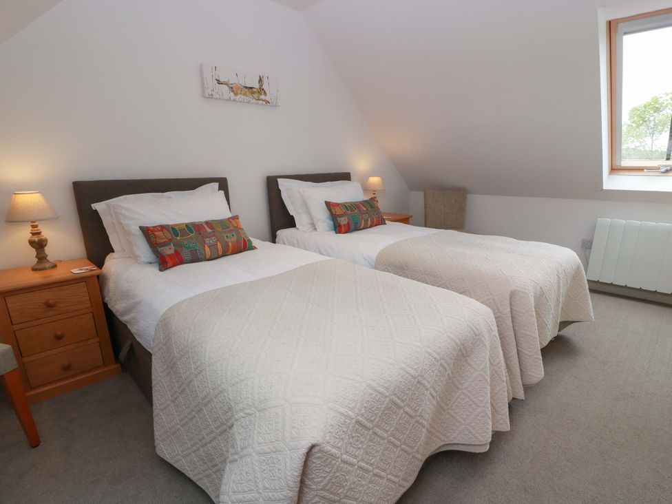 A bedroom with twin beds and a nightstand at Muirmailing Cottage in Plean near Stirling