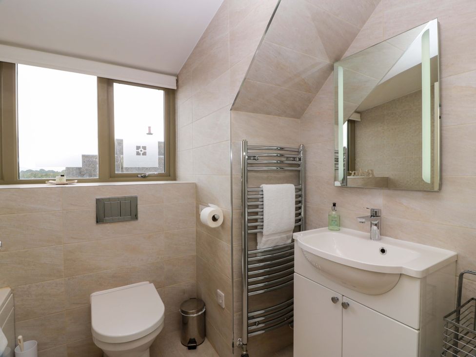 A bathroom with a toilet, sink, and mirror at Muirmailing Cottage Plean near Stirling