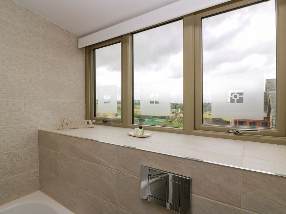 A bathroom with a bathtub and windows at Muirmailing Cottage Plean near Stirling