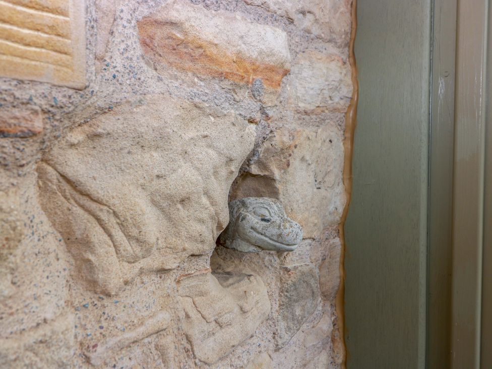 A stone wall with a creature sculpture at Muirmailing Cottage Plean near Stirling