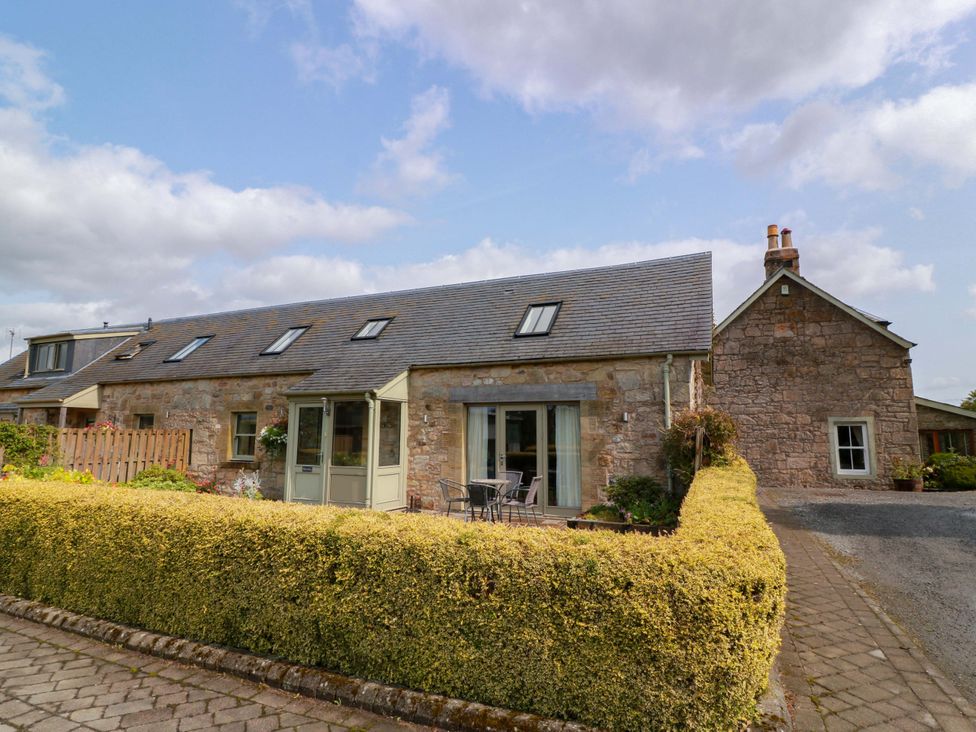 An outdoor view of a stone house with patio furniture at Muirmailing Cottage in Plean near Stirling