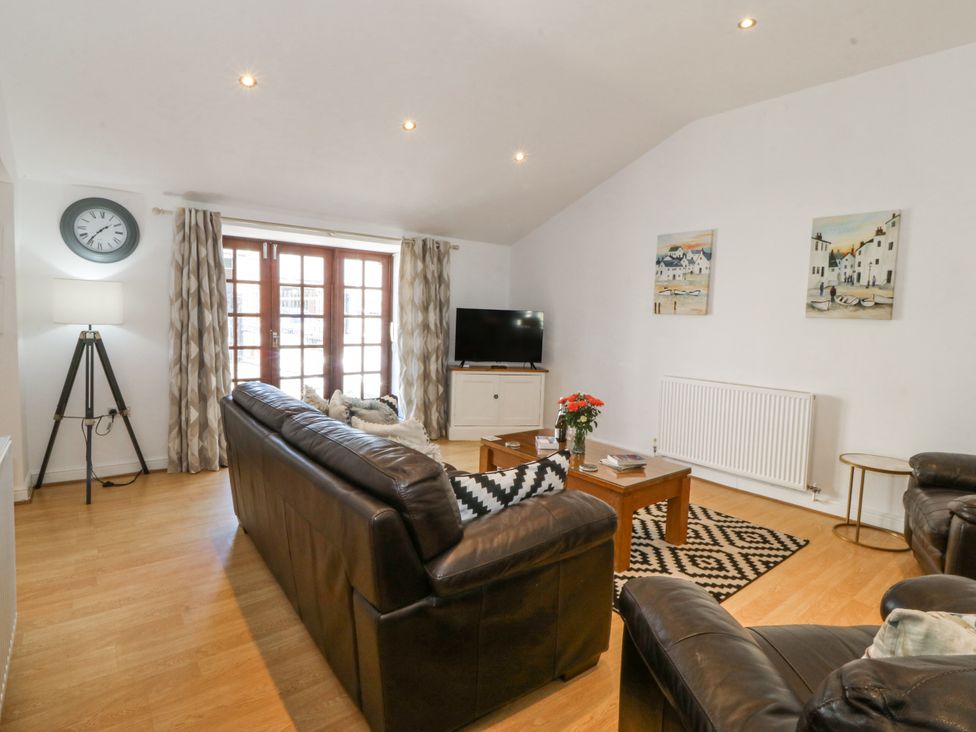 A living room with a sofa, table, and television at Maritime Mews, 6 The Oakleys Porthmadog