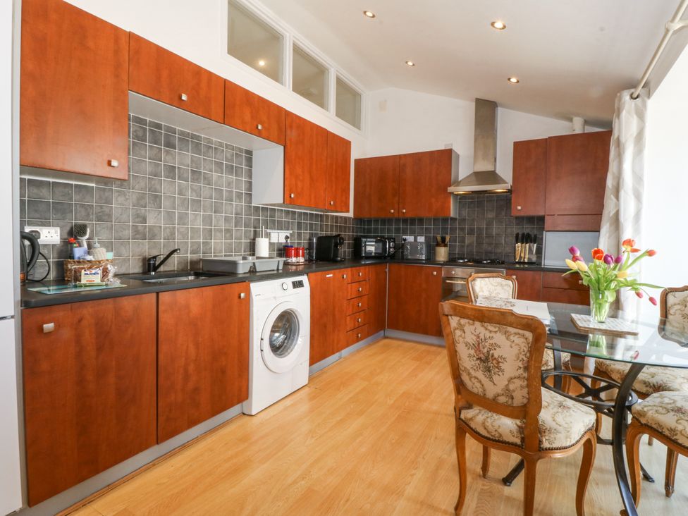 A kitchen with wooden cabinets and appliances at Maritime Mews, 6 The Oakleys, Porthmadog