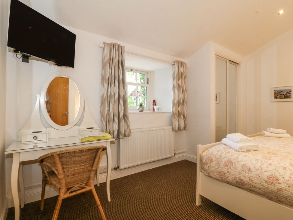 A bedroom with a bed, dressing table, and television at Maritime Mews, 6 The Oakleys Porthmadog