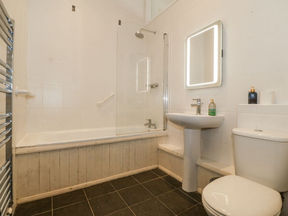 A bathroom with a shower over a bath and a sink at Maritime Mews, 6 The Oakleys Porthmadog
