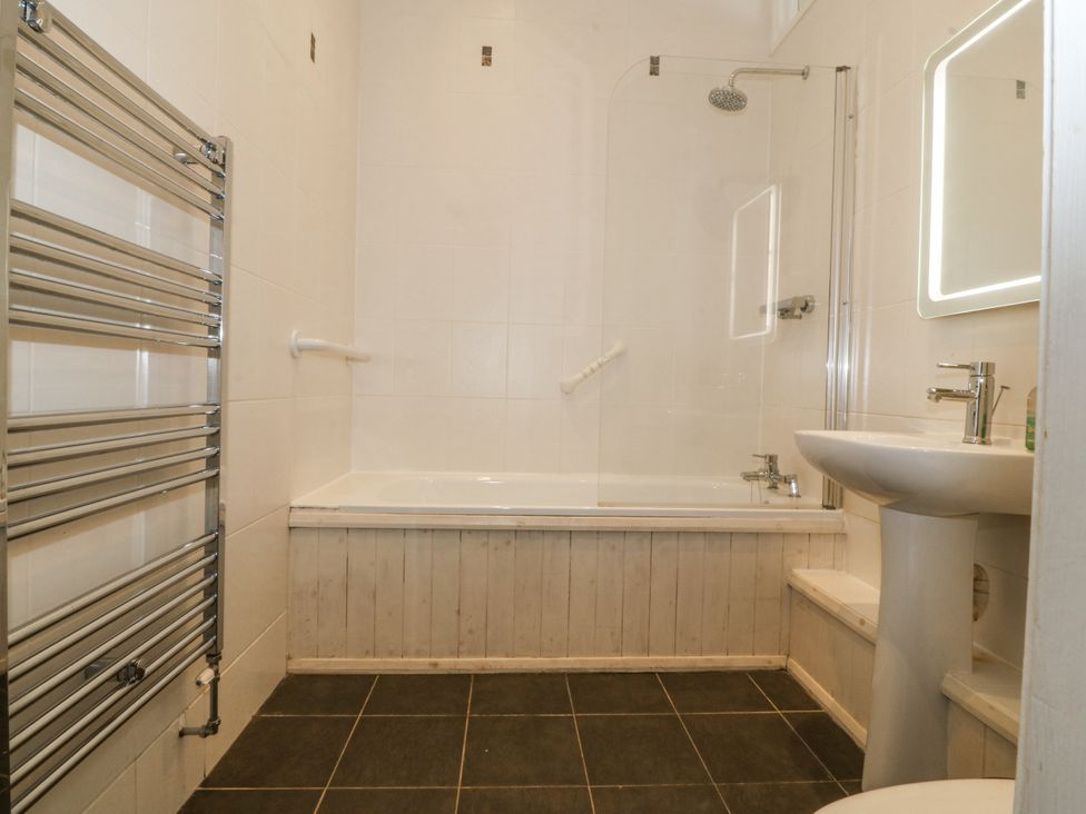 A bathroom with a bathtub, sink, and towel rail at Maritime Mews, 6 The Oakleys Porthmadog